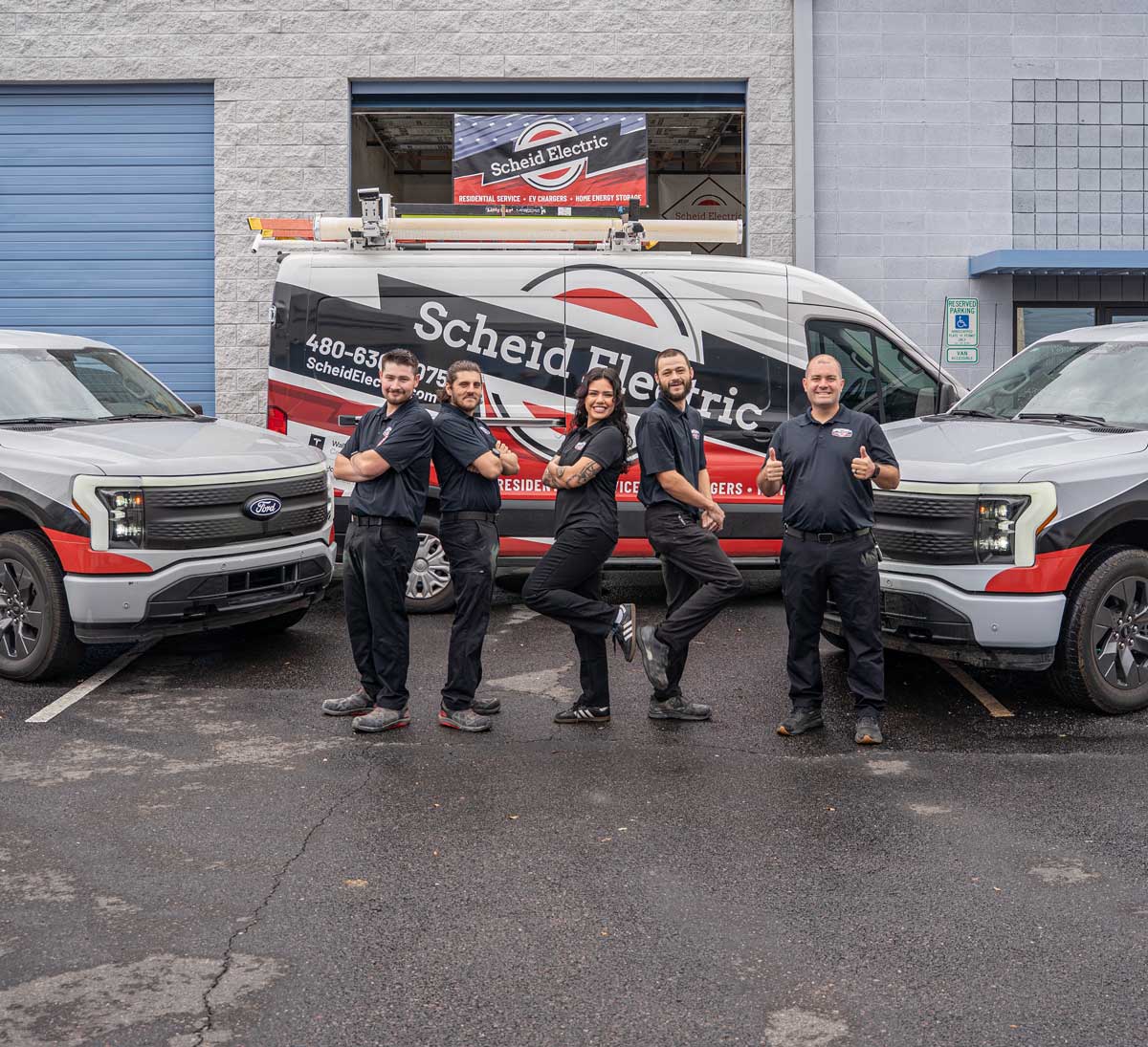 Team of electrician at Scheid Electric having fun before the work day with the fleet behind them.